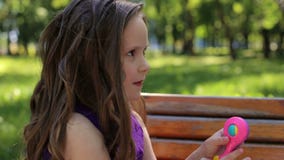 Um retrato de uma menina bonito de cinco anos velho em um banco em um parque do verão filme Um retrato de uma menina bonito de cinco anos velho em um banco em um parque do verão filme