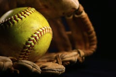 Um softball amarelo em uma luva velha, marrom, de couro imagem de stock Um softball amarelo em uma luva velha, marrom, de couro imagem de stock