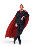 Um super-herói em um terno de negócio e em um cabo vermelho que inclinam-se em um objeto invisível no fundo branco Fotografia de Stock Royalty Free Um super-herói em um terno de negócio e em um cabo vermelho que inclinam-se em um objeto invisível no fundo branco Fotografia de Stock Royalty Free