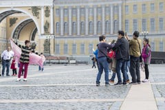 Um turista da mulher da aparência oriental que levanta para um grupo de compatriotas no quadrado do palácio de St Petersburg, Rús imagens de stock Um turista da mulher da aparência oriental que levanta para um grupo de compatriotas no quadrado do palácio de St Petersburg, Rús imagens de stock