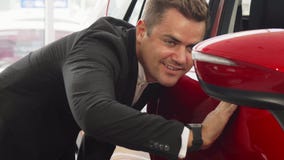 Um vendedor novo verifica a integridade do carro foto de stock Um vendedor novo verifica a integridade do carro foto de stock