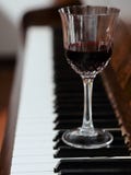 Um vidro do vinho tinto e do piano foto de stock Um vidro do vinho tinto e do piano foto de stock