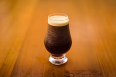 Um vidro frio da cerveja escura em uma superfície de madeira foto de stock Um vidro frio da cerveja escura em uma superfície de madeira foto de stock