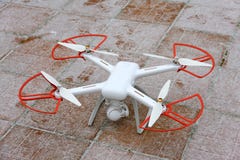 Um zangão do quadrocopter está na neve em uma telha vermelho-marrom pronto para voar no inverno foto de stock Um zangão do quadrocopter está na neve em uma telha vermelho-marrom pronto para voar no inverno foto de stock