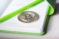 Um único bitcoin dourado em um bloco de notas verde foto de stock Um único bitcoin dourado em um bloco de notas verde foto de stock