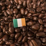 Uma bandeira da Irlanda colocada sobre feijões de café roasted fotos de stock Uma bandeira da Irlanda colocada sobre feijões de café roasted fotos de stock