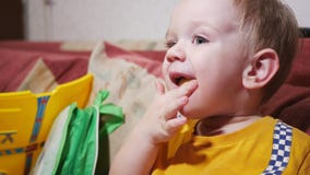 Uma criança está sentando-se no sofá em casa e na tevê de observação Coma varas e sorriso do milho filme Uma criança está sentando-se no sofá em casa e na tevê de observação Coma varas e sorriso do milho filme