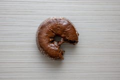 Uma filhós do chocolate que está sendo comida e colocada em uma tabela do café da manhã imagens de stock Uma filhós do chocolate que está sendo comida e colocada em uma tabela do café da manhã imagens de stock