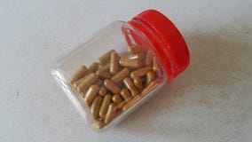 Uma garrafa de cápsulas chinesas da erva imagem de stock Uma garrafa de cápsulas chinesas da erva imagem de stock