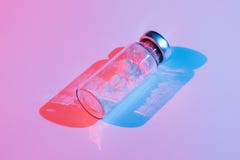 Uma garrafa de vidro com uma vacina na iluminação da cor imagem de stock Uma garrafa de vidro com uma vacina na iluminação da cor imagem de stock