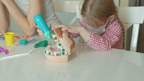 Uma jovem mulher e um molde da menina seus dentes do plasticine, introduzem seus dentes em uma maxila do brinquedo, removem as ci vídeos de arquivo Uma jovem mulher e um molde da menina seus dentes do plasticine, introduzem seus dentes em uma maxila do brinquedo, removem as ci vídeos de arquivo