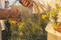 Uma menina e um homem no vestido eslavo tradicional branco envolvem uma grinalda de wildflowers frescos no por do sol Tradições d imagem de stock Uma menina e um homem no vestido eslavo tradicional branco envolvem uma grinalda de wildflowers frescos no por do sol Tradições d imagem de stock
