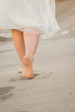 Uma menina em um vestido branco que anda na areia fotografia de stock royalty free Uma menina em um vestido branco que anda na areia fotografia de stock royalty free
