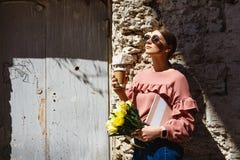 Uma menina está perto da parede urbana com uma xícara de café foto de stock royalty free Uma menina está perto da parede urbana com uma xícara de café foto de stock royalty free
