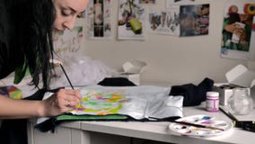 Uma morena aplica a pintura cor-de-rosa com uma escova à tela Uma ilustração de bull terrier é descrita no revestimento vídeos de arquivo Uma morena aplica a pintura cor-de-rosa com uma escova à tela Uma ilustração de bull terrier é descrita no revestimento vídeos de arquivo