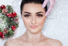 Uma mulher bonita obtém uma massagem facial no salão de beleza dos termas Close up da cara da mulher e da grinalda do ano novo imagens de stock royalty free Uma mulher bonita obtém uma massagem facial no salão de beleza dos termas Close up da cara da mulher e da grinalda do ano novo imagens de stock royalty free