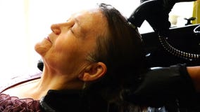 Uma mulher idosa admira a lavagem de sua cabeça em um salão de beleza filme Uma mulher idosa admira a lavagem de sua cabeça em um salão de beleza filme