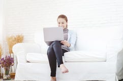 Uma mulher que veste uma camisa azul que senta-se em uma cadeira para ter um laptop fotos de stock royalty free Uma mulher que veste uma camisa azul que senta-se em uma cadeira para ter um laptop fotos de stock royalty free