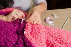 Uma mulher une uma curva branca a um pla lilás-cor-de-rosa à mão feito malha imagens de stock Uma mulher une uma curva branca a um pla lilás-cor-de-rosa à mão feito malha imagens de stock