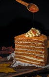 Uma parte de bolo de mel com favos de mel Em que o mel é derramado da parte superior de uma colher de madeira foto de stock royalty free Uma parte de bolo de mel com favos de mel Em que o mel é derramado da parte superior de uma colher de madeira foto de stock royalty free