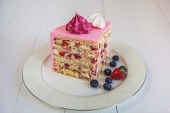 Uma parte de bolo morango-cremoso, coberta com um creme cor-de-rosa e decorada com marshmallows e bagas foto de stock Uma parte de bolo morango-cremoso, coberta com um creme cor-de-rosa e decorada com marshmallows e bagas foto de stock