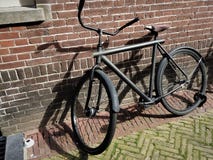 Uma posição velha da bicicleta ao lado de uma parede de pedra Paisagem da cidade de Amsterdão foto de stock royalty free Uma posição velha da bicicleta ao lado de uma parede de pedra Paisagem da cidade de Amsterdão foto de stock royalty free