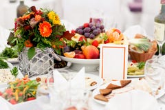 Uma tabela festiva no centro belamente decorada com uma refeição de que suportes um vaso com um ramalhete das flores, uma placa d fotografia de stock royalty free Uma tabela festiva no centro belamente decorada com uma refeição de que suportes um vaso com um ramalhete das flores, uma placa d fotografia de stock royalty free