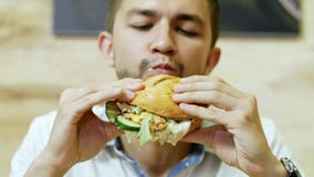 Un antropófago hambriento una hamburguesa jugosa en un restaurante de los alimentos de preparación rápida, comida deliciosa almacen de video Un antropófago hambriento una hamburguesa jugosa en un restaurante de los alimentos de preparación rápida, comida deliciosa almacen de video