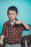 Un beau petit garçon dans sourires et prises de pyjamas dans sa main une brosse à dents sur un fond bleu photo libre de droits Un beau petit garçon dans sourires et prises de pyjamas dans sa main une brosse à dents sur un fond bleu photo libre de droits