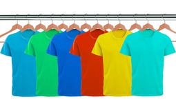 Un bon nombre de T-shirts sur des cintres d'isolement sur le blanc photographie stock libre de droits Un bon nombre de T-shirts sur des cintres d'isolement sur le blanc photographie stock libre de droits