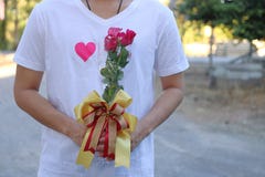 Un bouquet de belles roses rouges est tenu par le jeune homme bel dans la chemise blanche Jour du ` s de Valentine ou concept de Image stock Un bouquet de belles roses rouges est tenu par le jeune homme bel dans la chemise blanche Jour du ` s de Valentine ou concept de Image stock