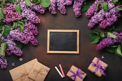 Un bouquet des lilas avec le panneau de craie, boîte-cadeau, enveloppe de métier sur le fond rouillé photographie stock Un bouquet des lilas avec le panneau de craie, boîte-cadeau, enveloppe de métier sur le fond rouillé photographie stock