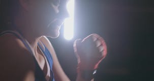 Un boxeador hermoso de la mujer entrena en un gimnasio oscuro y resuelve sacadores en la cámara lenta Vista lateral tiro del stea almacen de metraje de vídeo Un boxeador hermoso de la mujer entrena en un gimnasio oscuro y resuelve sacadores en la cámara lenta Vista lateral tiro del stea almacen de metraje de vídeo