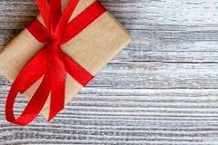 Un boîte-cadeau, admirablement enveloppé avec le papier d'emballage et l'arc de ruban et grand rouge sur le fond en bois avec l'e images libres de droits Un boîte-cadeau, admirablement enveloppé avec le papier d'emballage et l'arc de ruban et grand rouge sur le fond en bois avec l'e images libres de droits