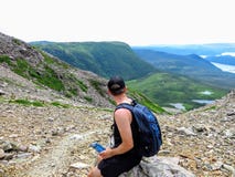 Un caminante masculino joven que admira las visiones espectaculares desde encima de Gros Morne Mountain en Gros Morne National Pa foto de archivo libre de regalías Un caminante masculino joven que admira las visiones espectaculares desde encima de Gros Morne Mountain en Gros Morne National Pa foto de archivo libre de regalías