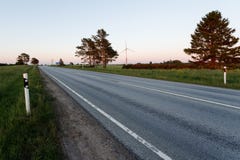 Un camino vacío que corre con un paisaje rural debajo de un cielo de la puesta del sol con luz del sol fotos de archivo libres de regalías Un camino vacío que corre con un paisaje rural debajo de un cielo de la puesta del sol con luz del sol fotos de archivo libres de regalías