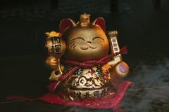Un chat chanceux chinois d'or avec sa patte gauche augmentée, sur une surface en bois rustique photographie stock Un chat chanceux chinois d'or avec sa patte gauche augmentée, sur une surface en bois rustique photographie stock