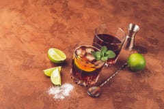 Un cocktail des glaçons de rhum et de la chaux juteuse dans des gobelets en verre sur un fond brun foncé Boisson alcoolisée forte photo stock Un cocktail des glaçons de rhum et de la chaux juteuse dans des gobelets en verre sur un fond brun foncé Boisson alcoolisée forte photo stock