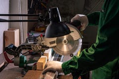 Un constructeur d'homme scie un conseil avec une scie circulaire dans l'atelier photographie stock Un constructeur d'homme scie un conseil avec une scie circulaire dans l'atelier photographie stock