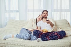 Un couple regardant la TV se reposer sur le divan dans la chambre image stock Un couple regardant la TV se reposer sur le divan dans la chambre image stock