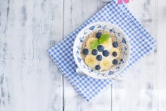 Un cuenco de cereales con los arándanos y las frambuesas con el yogur en una tabla de madera, desayuno sano, fotografía de archivo Un cuenco de cereales con los arándanos y las frambuesas con el yogur en una tabla de madera, desayuno sano, fotografía de archivo