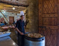 Un cuisinier se tient près d'un grand plateau avec un plat de viande et des attentes des visiteurs dans un restaurant de bord de photos stock Un cuisinier se tient près d'un grand plateau avec un plat de viande et des attentes des visiteurs dans un restaurant de bord de photos stock