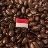 Un drapeau du Monaco placé au-dessus des grains de café rôtis photos stock Un drapeau du Monaco placé au-dessus des grains de café rôtis photos stock