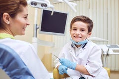 Un enfant de garçon est un dentiste avec un patient à une clinique dentaire photographie stock Un enfant de garçon est un dentiste avec un patient à une clinique dentaire photographie stock