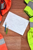Un foglio di carta sgualcito con due matite circondate dalle uniformi funzionanti verdi ed arancio Natura morta connessa con la r immagini stock libere da diritti Un foglio di carta sgualcito con due matite circondate dalle uniformi funzionanti verdi ed arancio Natura morta connessa con la r immagini stock libere da diritti