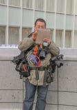 Un fotógrafo que lleva cámaras y bolsas múltiples imagen de archivo libre de regalías Un fotógrafo que lleva cámaras y bolsas múltiples imagen de archivo libre de regalías