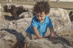 Un garçon d'enfant en bas âge marche soigneusement par quelques grandes roches image stock Un garçon d'enfant en bas âge marche soigneusement par quelques grandes roches image stock