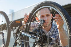 Un giovane padrone maschio dell'ingegnere sta esaminando una ruota di bicicletta fotografie stock Un giovane padrone maschio dell'ingegnere sta esaminando una ruota di bicicletta fotografie stock