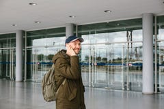Un giovane turista maschio all'aeroporto o vicino ad un centro commerciale o ad una stazione chiama un taxi o i colloqui su un te fotografia stock Un giovane turista maschio all'aeroporto o vicino ad un centro commerciale o ad una stazione chiama un taxi o i colloqui su un te fotografia stock