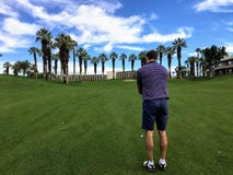 Un golfista de sexo masculino joven que se alinea su tiro de acercamiento desde el medio del espacio abierto en un par 4 en un ca imágenes de archivo libres de regalías Un golfista de sexo masculino joven que se alinea su tiro de acercamiento desde el medio del espacio abierto en un par 4 en un ca imágenes de archivo libres de regalías
